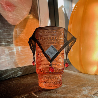 home bar with silk drink marker draped over orange textured water glass deep red glass roses as charms, slug is attempting to drink out of the glass